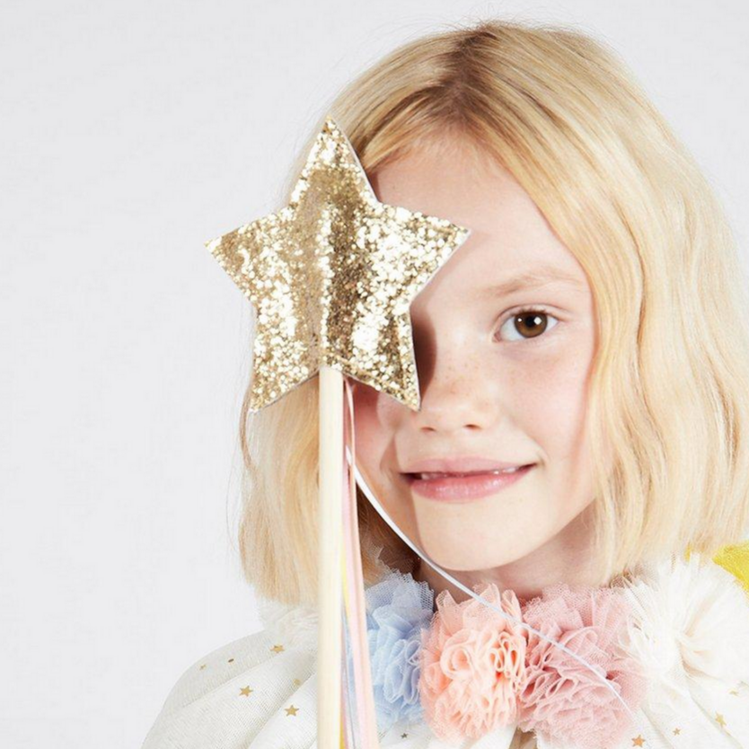 little girl with pompom tulle color holding glittered star wand up to eye