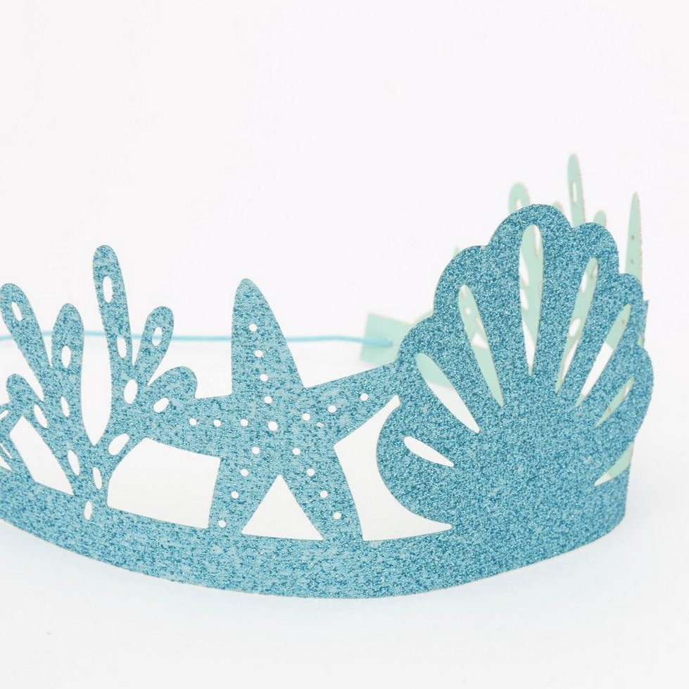 side view of aqua gliitered paper crown with elastic and cut designs of starfish, shells and sea plants