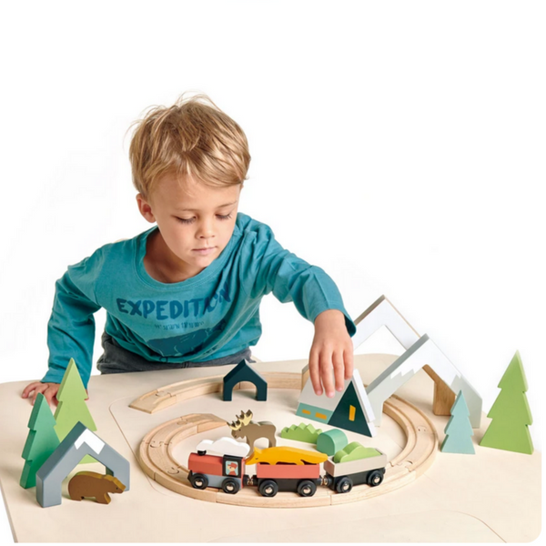 child playing with trees and train