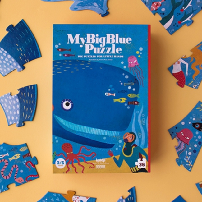 A 36-piece puzzle box with ocean animals like a whale, shark, and crab, and a colorful background. The box is open, revealing the puzzle pieces, which are spread around it.