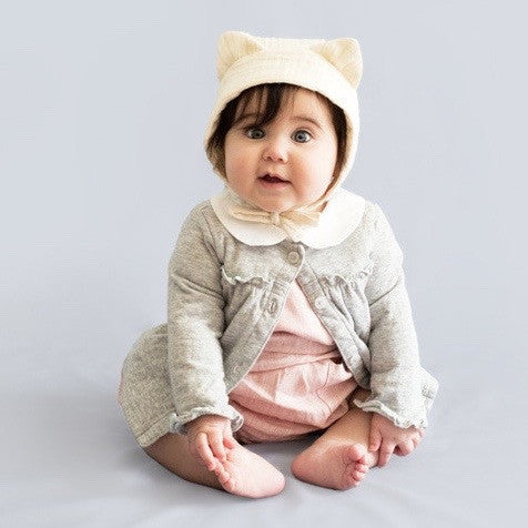 baby wearing crean cat eared bonnet