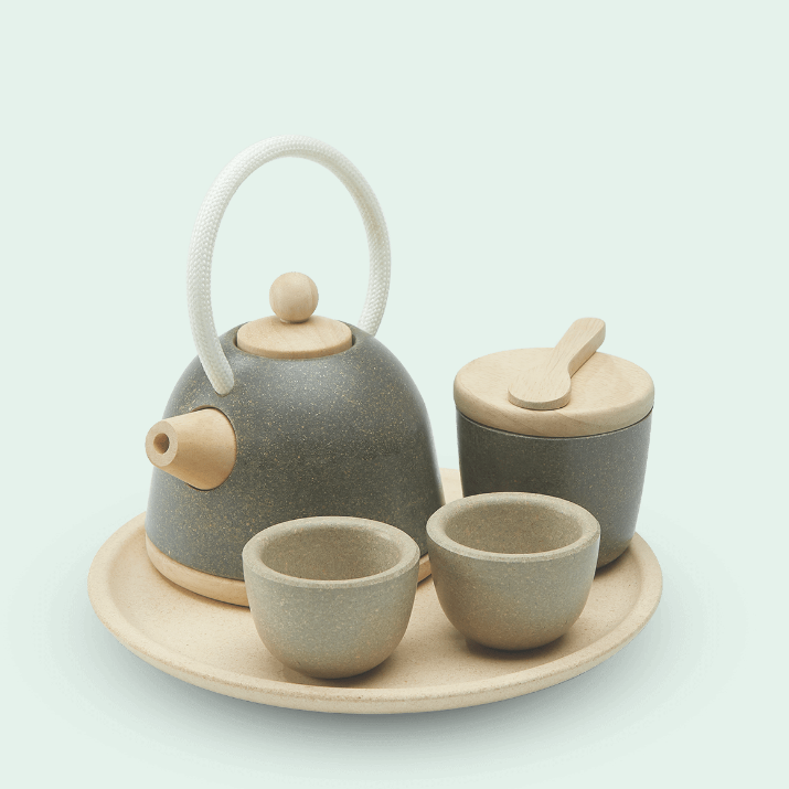 A pretend tea set designed for children, including a teapot, two cups, a pitcher, and a tray, all in beige and green colors.