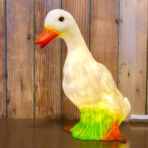 realistic white duck lamp with orange feet and beak and patch of grass in between legs