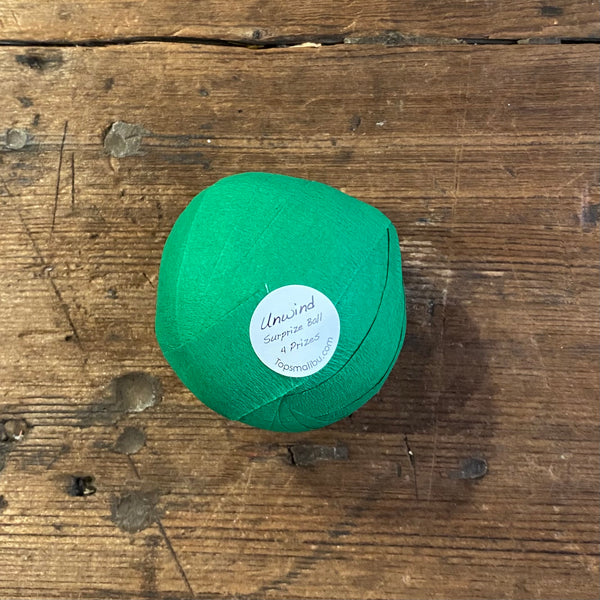 sticker on bottom of dark green surprize balls that say "unwind! Surprize ball 4 fun prizes