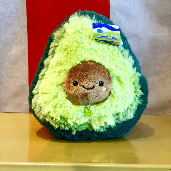 avocado plush with face on pit in front of striped curtain